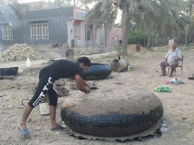 Applying mud as a protective layer to exterior of Guffa coracles Hilla, Iraq (Rashad Salim, Safina Projects, 2018)